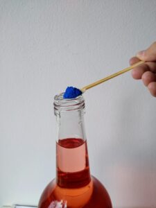 ein kleiner Löffel blaues Mica-Pulver wird in eine Flasche mit roter Flüssigkeit gefüllt, Schreibanlass Halloween Deko